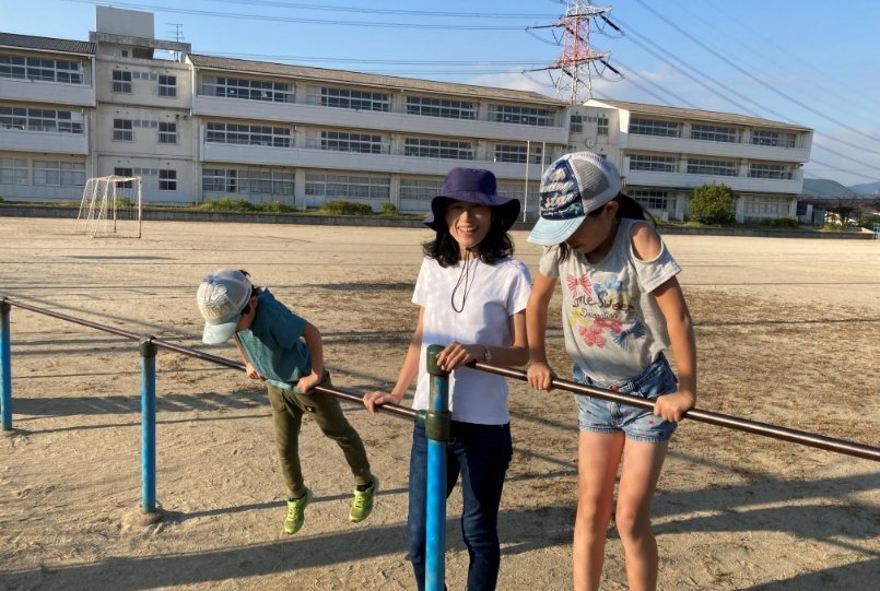 校庭で鉄棒をして遊ぶ子供たちと藤木さん