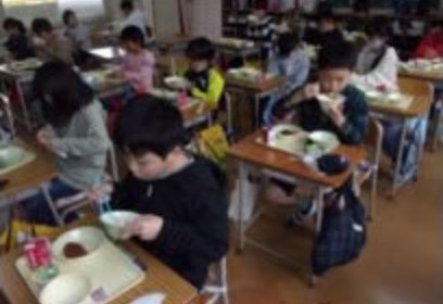 小学校の教室で子供たちが給食を食べている画像
