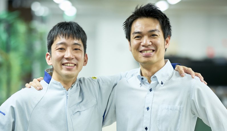 笑顔で肩を組む二人の社員