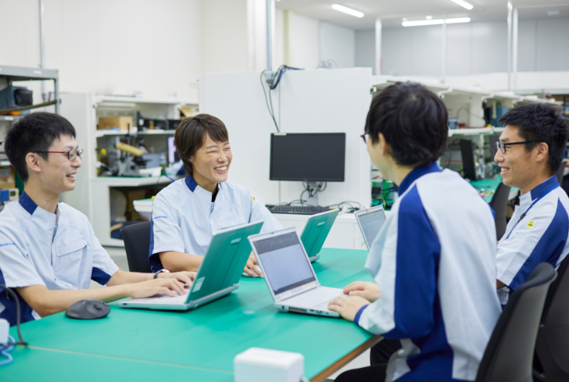 テーブルで3名の男性社員と会話する貝野さん