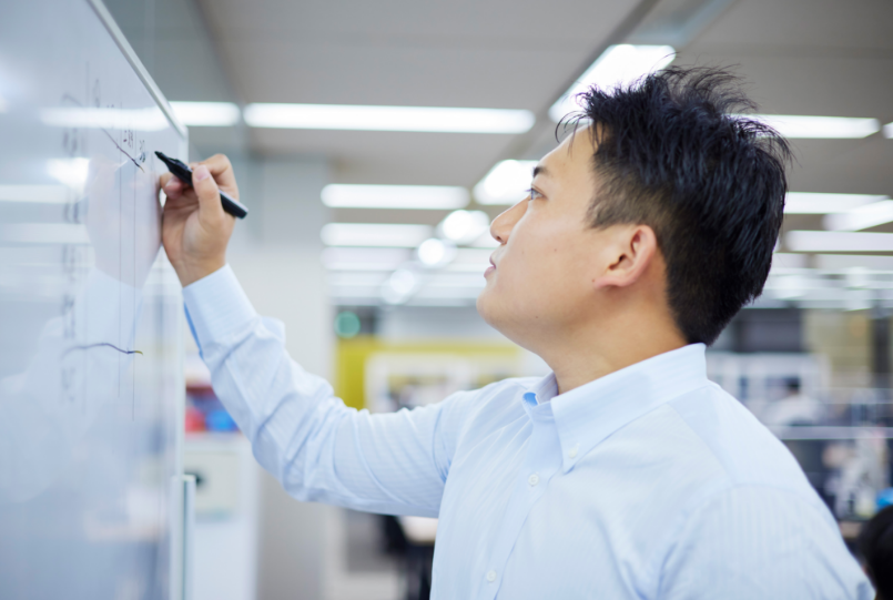 社内でホワイトボードに向かってグラフを書く宮下さん