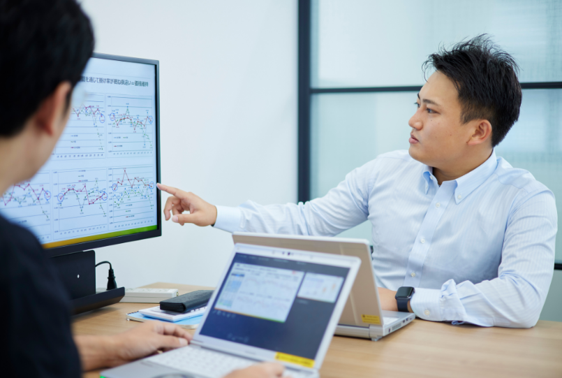 打ち合わせ中にモニターを指差し説明する宮下さん