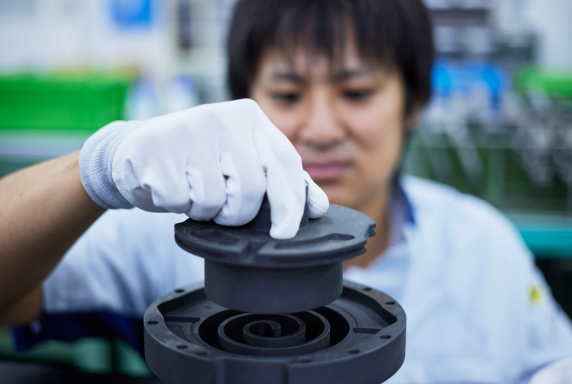 機械の部品を手に持ち作業をする大城さん